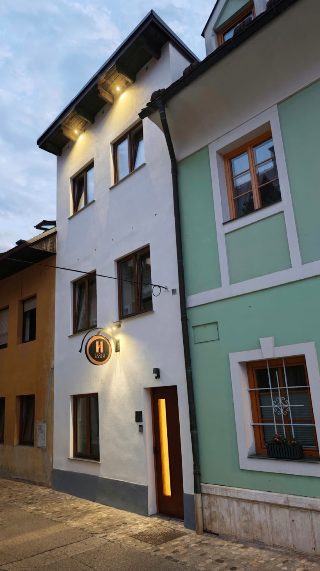The lit façade of Hucho House at dusk in the old town of Kranj